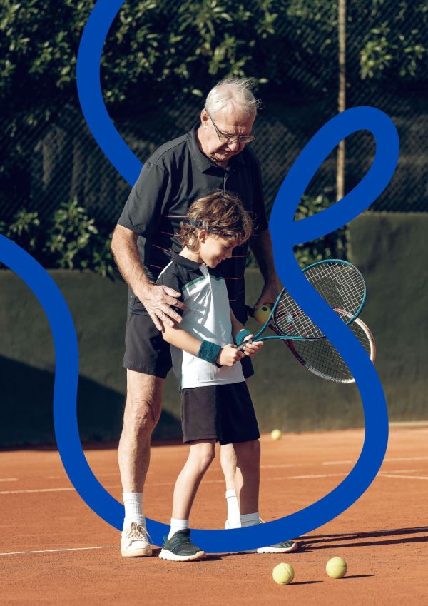 Persona mayor jugando al tenis con un niño